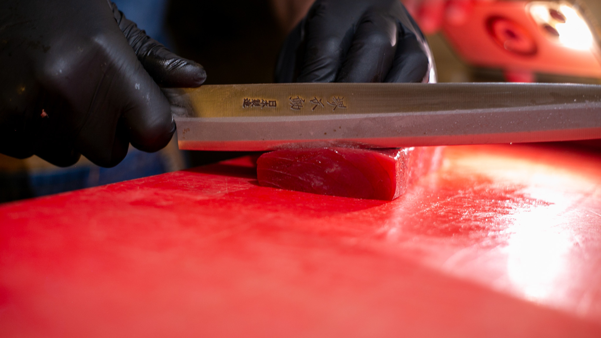 Chef cortando lingote de atún oro, tras un meticuloso proceso de ronqueo de atún, listo para ser servido en un evento gourmet.