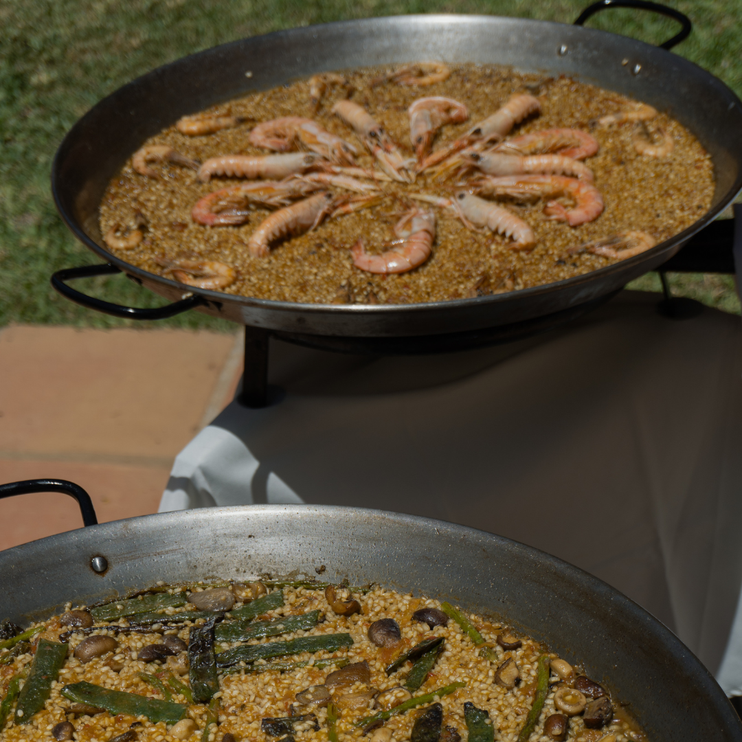 Paella de mariscos y paella valenciana en un evento, preparadas en directo por un chef arrocero, ofreciendo dos sabores auténticos y tradicionales.