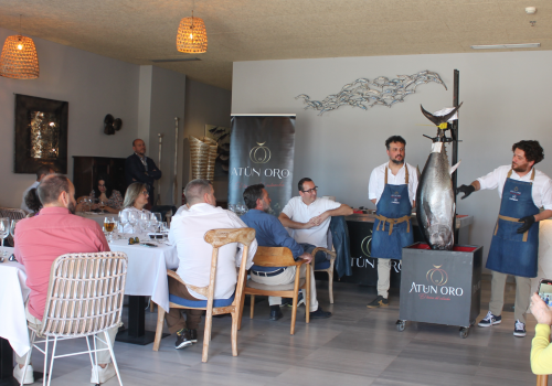 Chef especializado en ronqueo de atún presentando el atún fresco durante una demostración en vivo en un evento, explicando el proceso a los asistentes.